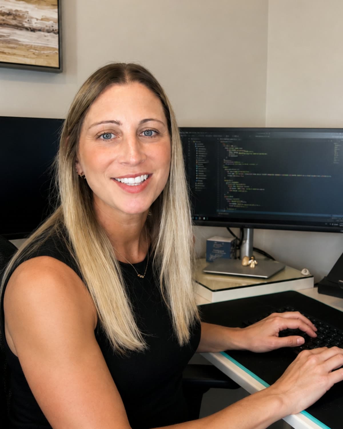 Chelsea Hulin at her desk, writing code on a dual-monitor setup